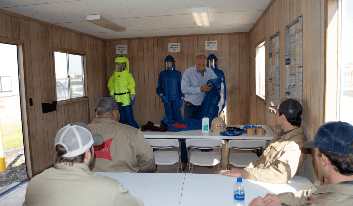Mannequins in PPE suits stand behind an instructor durning ParFab's Alky Training demonstration.